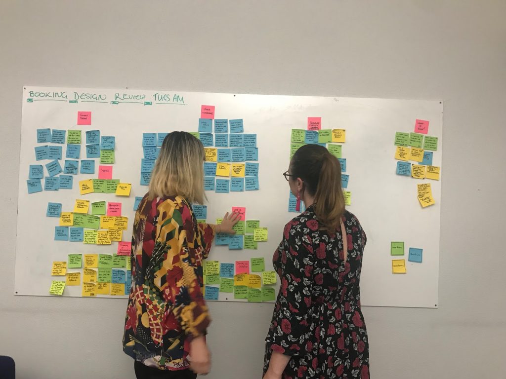 User researchers mapping in front of a wall of post it notes